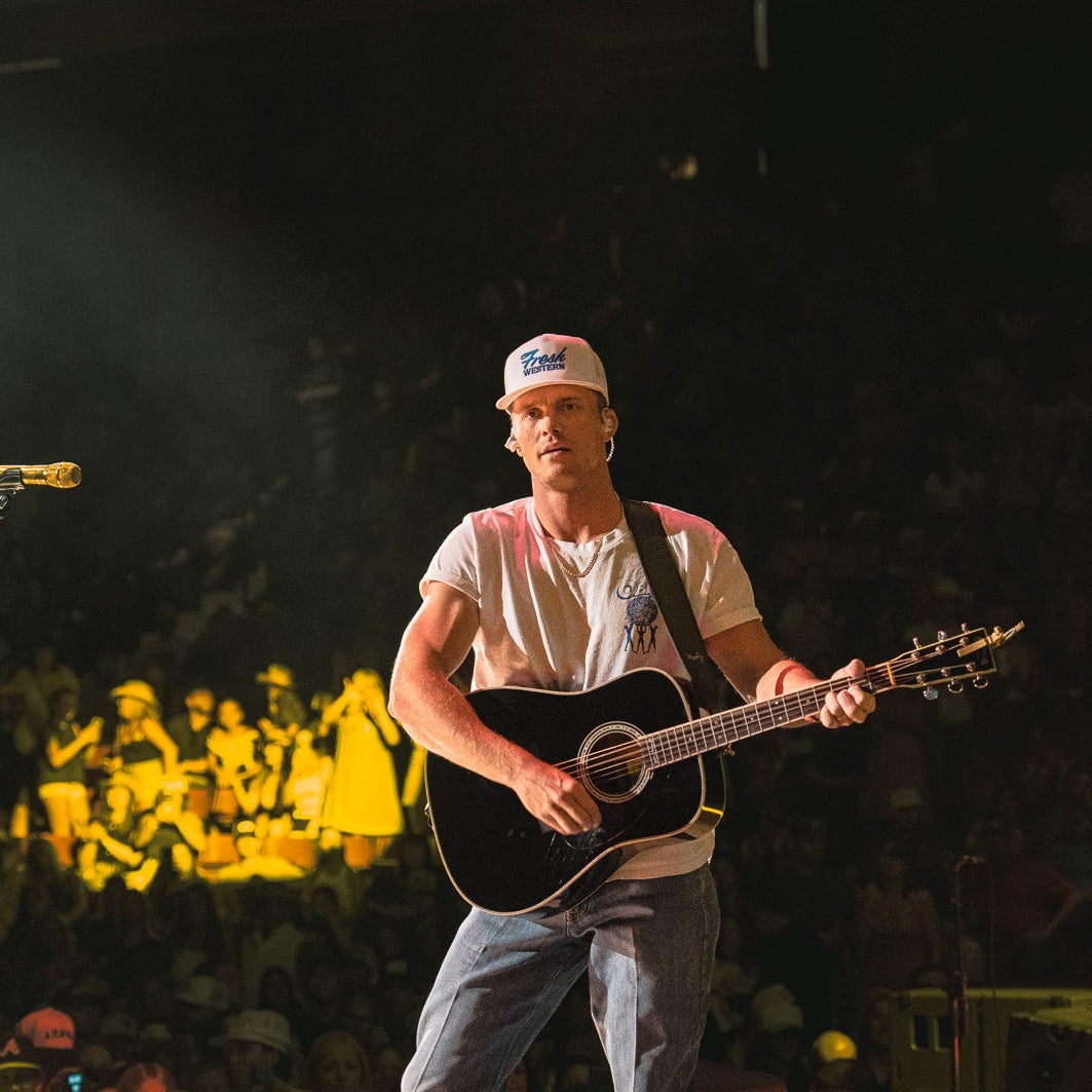 Parker McCollum wearing Fresh Western White Snapback Tour Hat with Royal Blue Logo on stage performing