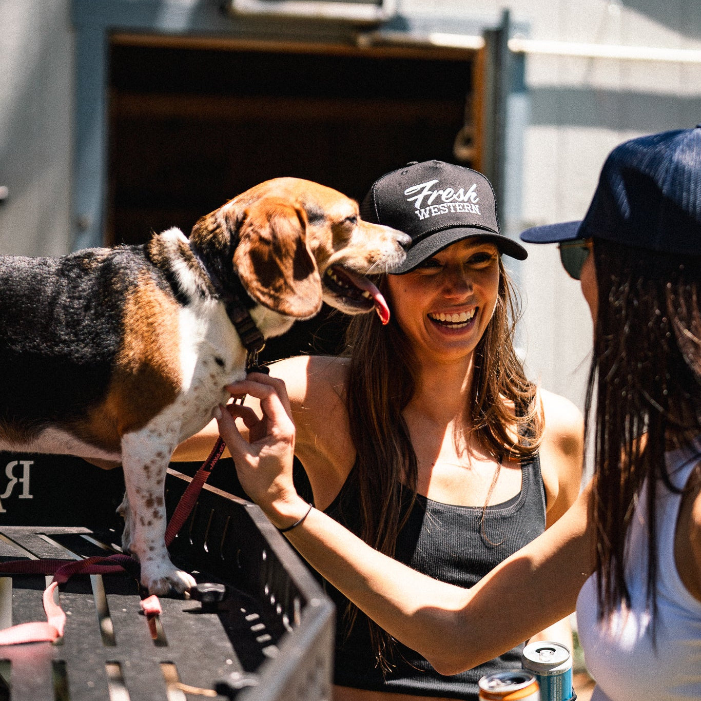 Two women and a dog in an outdoor setting, with one woman wearing Black Fresh Western Retro Rope Trucker Hat