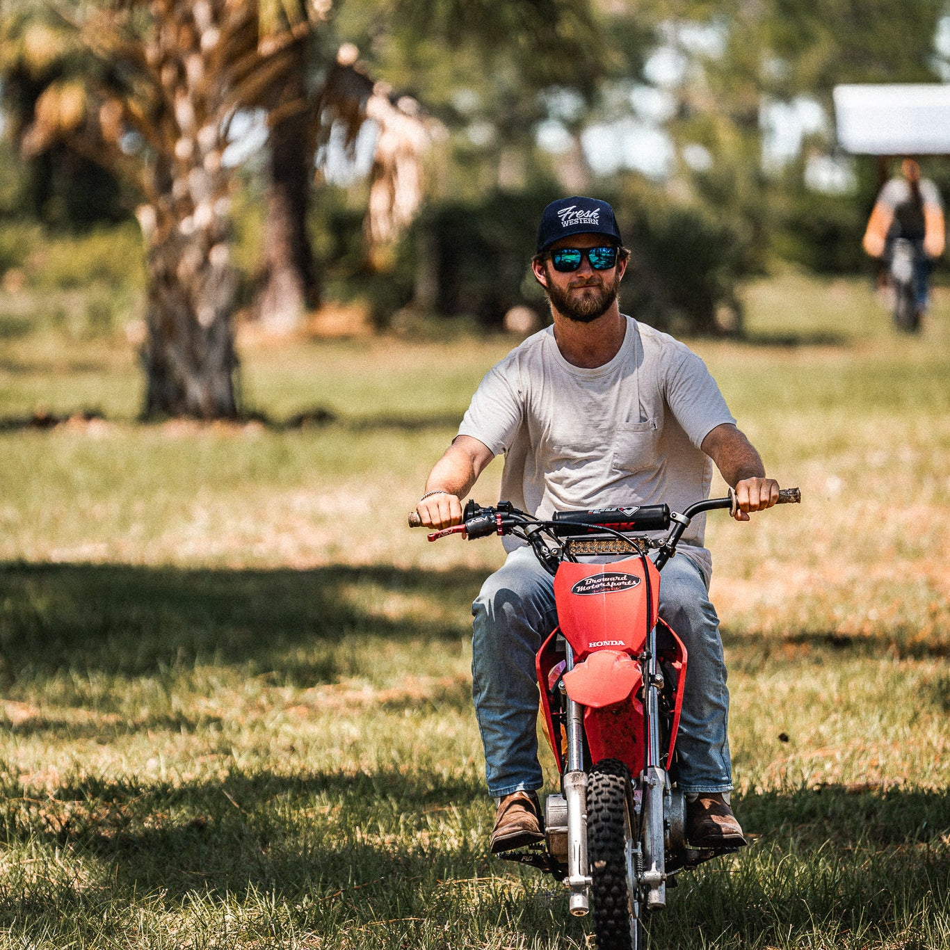 Man riding dirt bike wearing a Navy 5-Panel Truck Hat with White Fresh Western Embroidery Logo